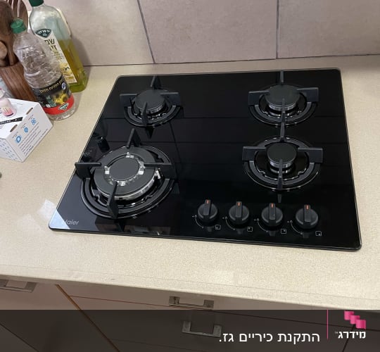 כיריים גז שחורות עם ארבעה מבערים וכפתורי שליטה